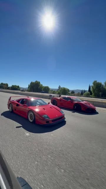 Two red Ferraris travelling together in the sunshine