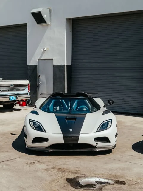 The white Koenigsegg with a blue cabin outside the workshop