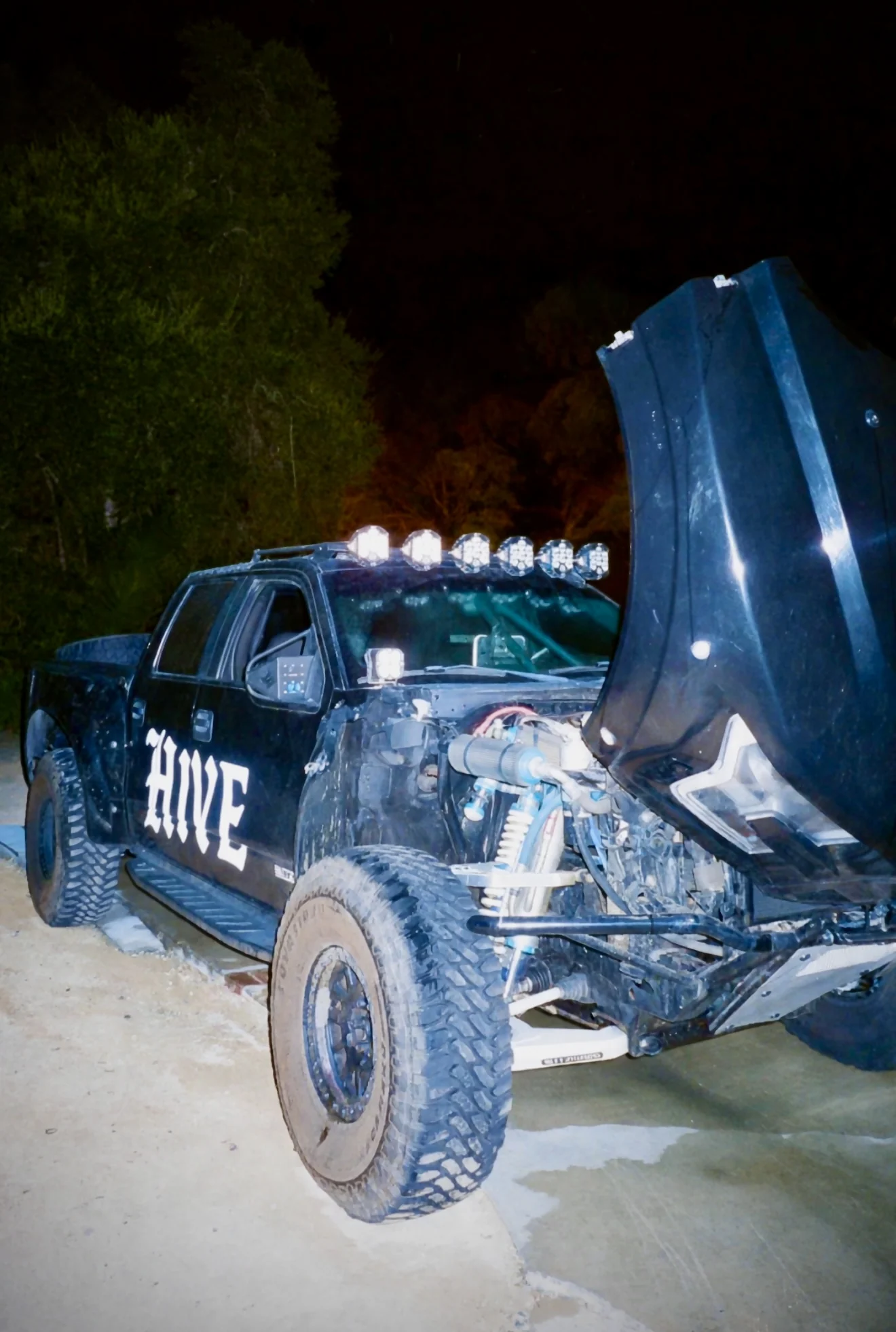 The black HIVE Raptor at night with its bonnet raised and off-road suspension visible